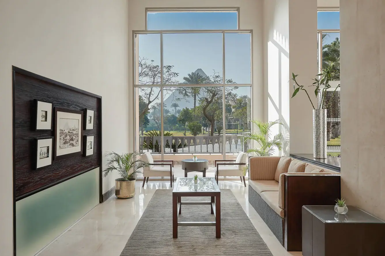 Lobby lounge at Mena House Hotel Cairo with historic photographs and a Pyramid view through floor-to-ceiling windows
