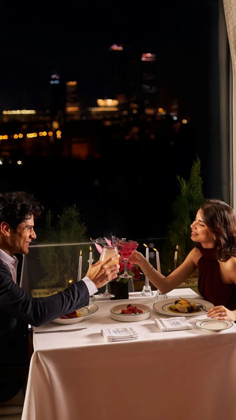 Couple toasting over a romantic dinner at The Nile Ritz-Carlton Cairo overlooking the city at night