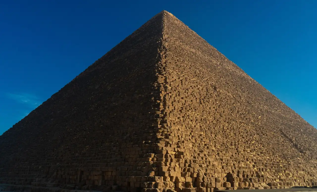 The Great Sphinx of Giza with a pyramid rising behind it in the desert, Egypt