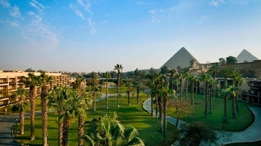 Landscaped grounds at Marriott Mena House Cairo with palm trees and the Pyramids in the distance