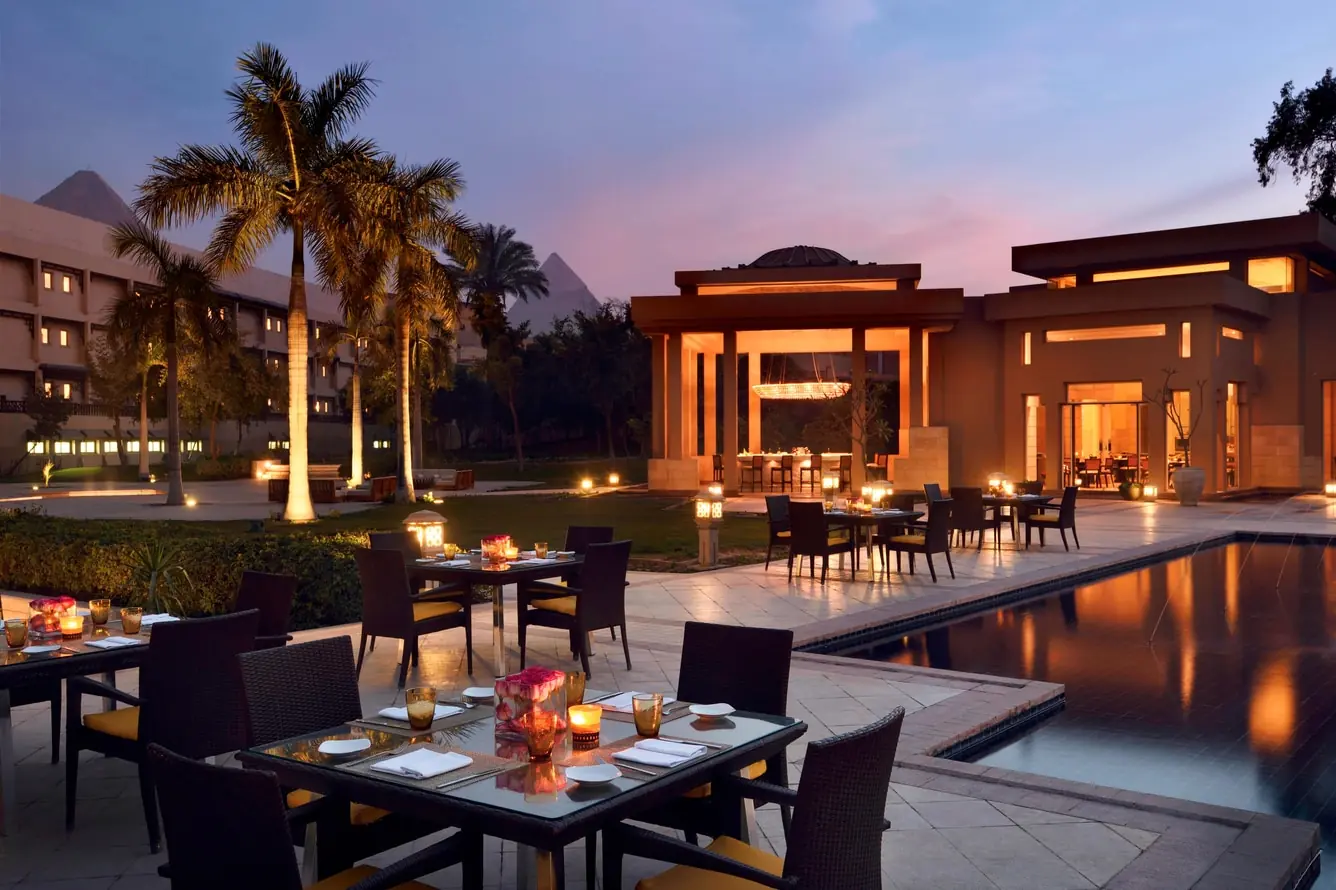 Poolside dining terrace at Marriott Mena House Cairo with views of the Great Pyramids at dusk