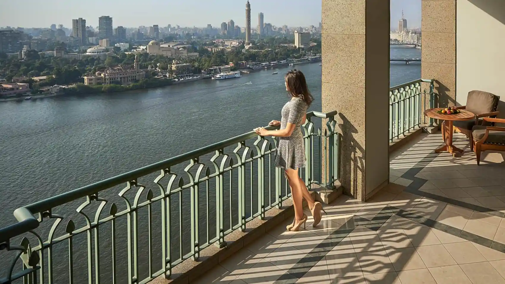 Guest on a balcony at Four Seasons Nile Plaza Cairo overlooking the Nile and Cairo skyline